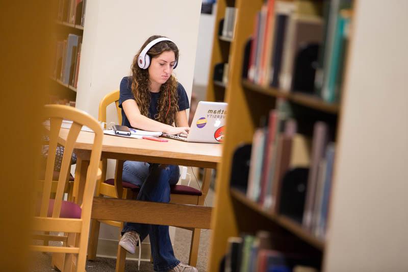 Photo of a Chatham University student working at a computer in the library.
